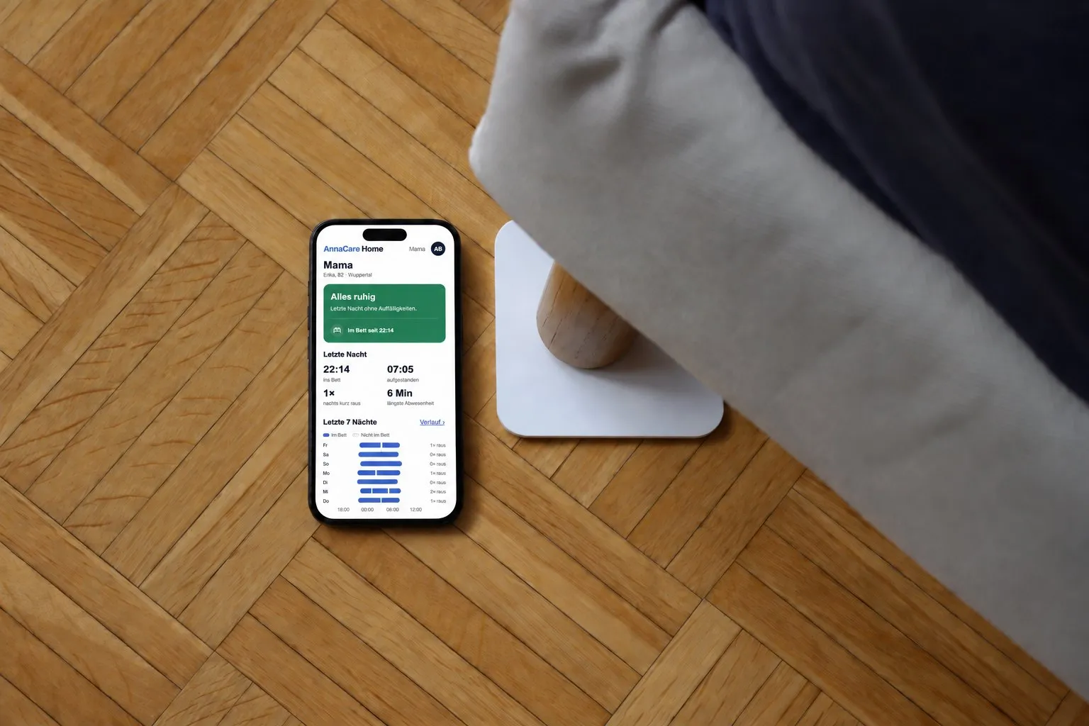 Smartphone mit der AnnaCare-Home-App neben dem Sensorpad unter einem Bettfuß